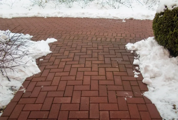 Garden stone path with snow. Brick sidewalk.